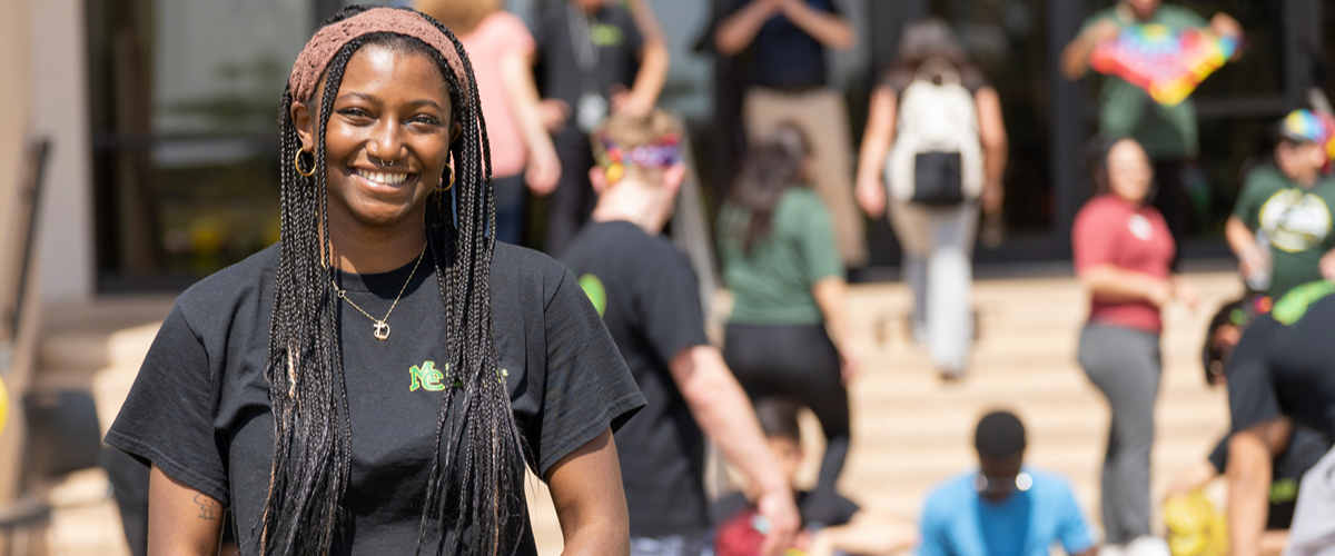 mc nursing student poses in front of library steps full of students