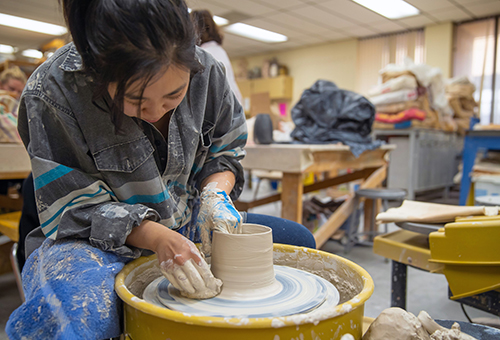 Art student creating a mug in the ceramics class