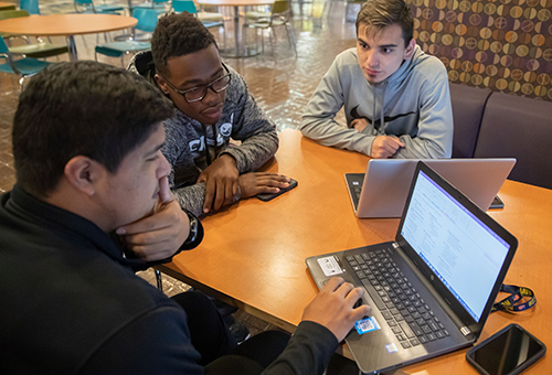 Computer Science students working with laptop/tablet devices in the library