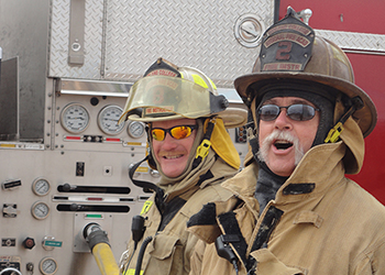 Two Fire Science instructors standing by the fire truck controls