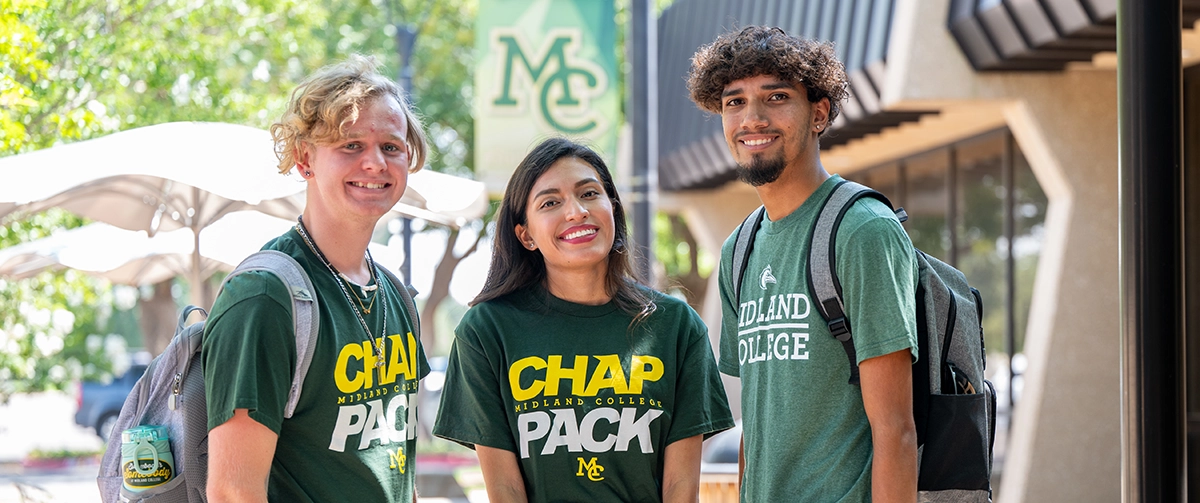 Three Midland College students in Chap Pack shirts standing together on campus