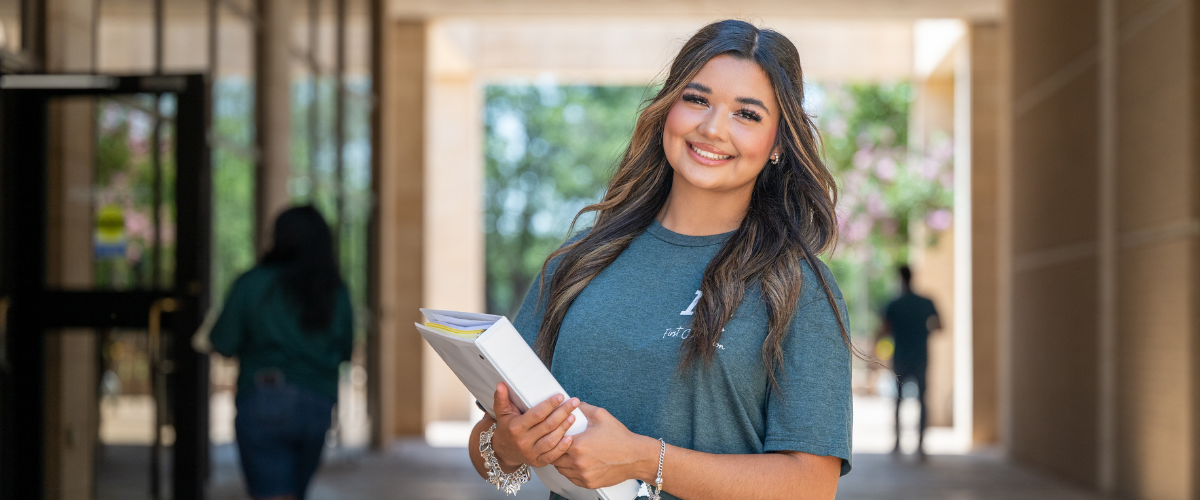 MC student holding a bind in the breezeway