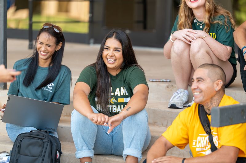 The image to use for this article. Listing image managed through RSS tab. four MC students from different backgrounds sit on the steps of the Learning Resource Center smiling for the camera